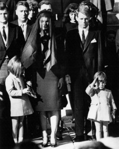 Jacqueline and children at the funeral of President John F. Kennedy. John Jr. salutes passing coffin.